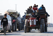 Displaced people who fled from Aleppo countryside, ride on a vehicle with belongings in Tabqa