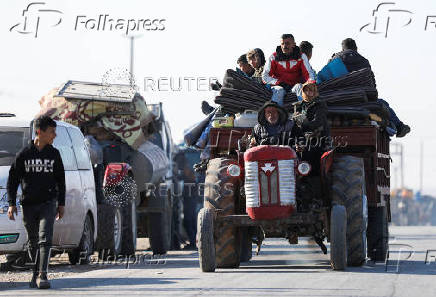 Displaced people who fled from Aleppo countryside, ride on a vehicle with belongings in Tabqa