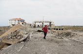 A man walks near a damaged site at the Lebanese-Syrian border crossing of Arida