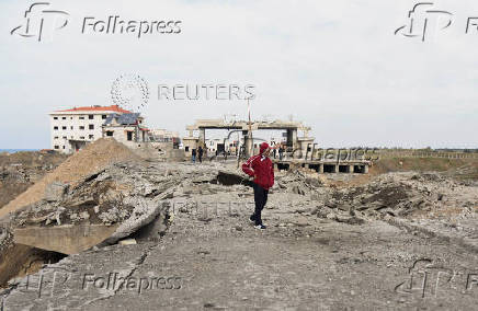 A man walks near a damaged site at the Lebanese-Syrian border crossing of Arida