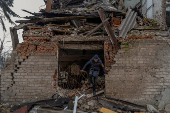 Mykola searchers for firewood in a building damaged by Russian military strikes in Pokrovsk