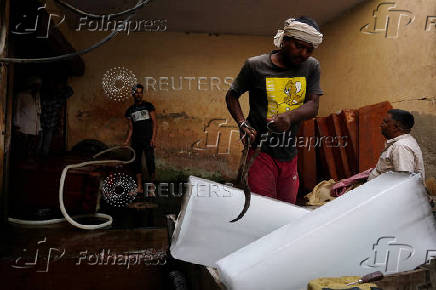 FILE PHOTO: A worker loads ice blocks into a vehicle at a factory on a hot summer day in Karnal