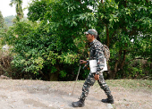 A Central Reserve Police Force (CRPF) personnel carries security equipment as he treks to reach a remote polling station inside Buxa Tiger Reserve forest