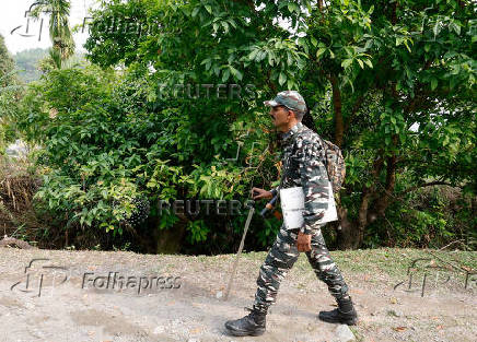 A Central Reserve Police Force (CRPF) personnel carries security equipment as he treks to reach a remote polling station inside Buxa Tiger Reserve forest