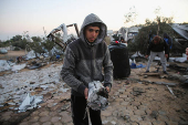 Palestinians inspect the damage at a tent camp sheltering displaced people, in Khan Younis