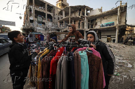 Firas, 15, a street vendor  jokes with his friends at the street market, in Douma