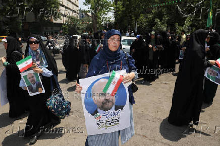 Supporters of Iranian presidential candidate Mohammad Bagher Ghalibaf hold posters of him on a street in Tehran