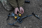 Policeman of the 'Khyzhak' Brigade attaches custom miniature drop bombs to a drone at a position in a front line near the town of Toretsk