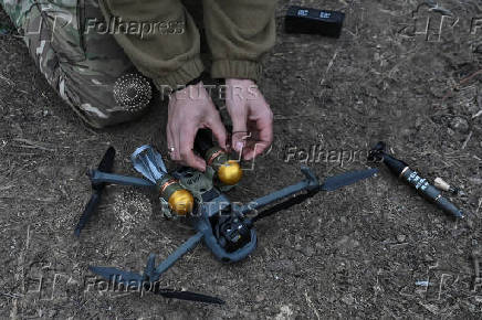 Policeman of the 'Khyzhak' Brigade attaches custom miniature drop bombs to a drone at a position in a front line near the town of Toretsk