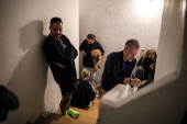 People take cover in the stairway of a building, while sirens sound in Tel Aviv