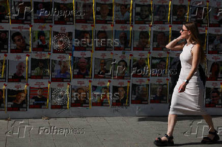 People walk past posters with pictures of hostages kidnapped in the October 7 attack by Hamas, in Tel Aviv