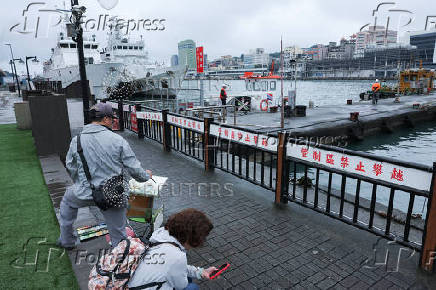 A man paints at a port in Keelung
