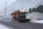 A snow plough operates on the A9 at the Drumochter pass, Scotland