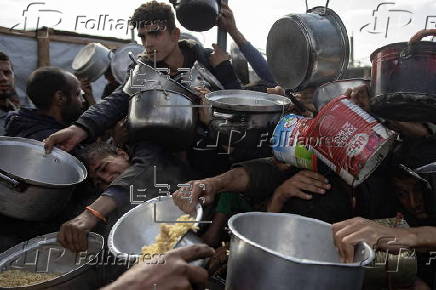 Displaced Palestinians collect donated food in Khan Yunis, southern Gaza