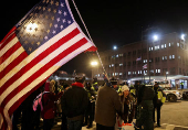 A man holds a U.S. flag as people wait outside the DC Central Detention Facility in Washington