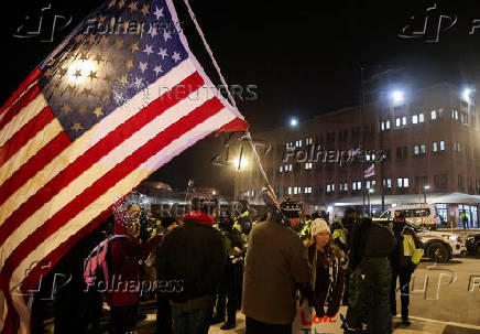 A man holds a U.S. flag as people wait outside the DC Central Detention Facility in Washington