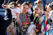 Kimono-clad young women pose for a photograph outside the venue for their Coming of Age Day celebration ceremony in Yokohama