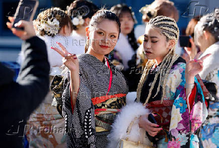 Kimono-clad young women pose for a photograph outside the venue for their Coming of Age Day celebration ceremony in Yokohama