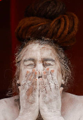 A Naga Sadhu or Hindu holy man smears ash outside his tent during  the 