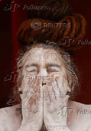 A Naga Sadhu or Hindu holy man smears ash outside his tent during  the 