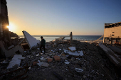 A Palestinian boy walks amidst the debris of a building destroyed during the Israeli offensive, at a beach in Gaza City
