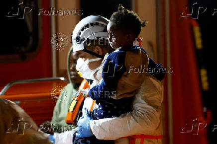 A rescue worker carries a migrant child before disembarking from a Spanish coast guard vessel at the port of Arguineguin, on the island of Gran Canaria