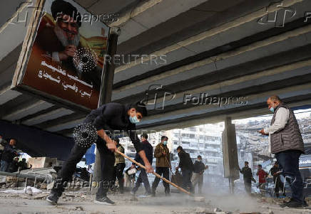 Members of Imam al-Mahdi scouts clean rubble and debris from damaged buildings in Beirut's southern suburbs