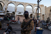 A fighter of the ruling Syrian body flashes a victory sign as he stands outside the Umayyad Mosque, in Damascus