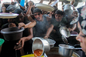 Palestinians gather to receive food cooked by a charity kitchen, amid the Israel-Hamas conflict, in the northern Gaza Strip