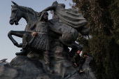 Boys play on the Salah Al Din Statue, in Damascus