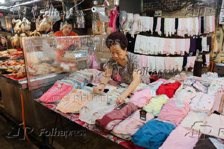 A person organizes her shop at a market in Keelung