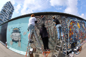 Conservators work beside a mural painted on a segment of the East Side Gallery in Berlin