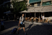 A tourist carries his luggage in Athens