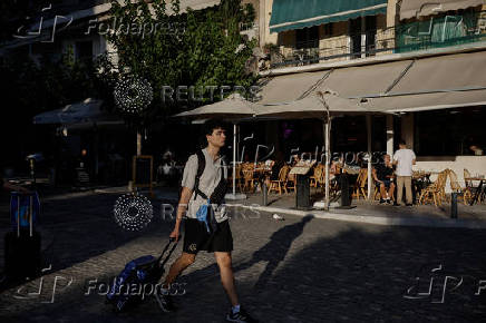 A tourist carries his luggage in Athens