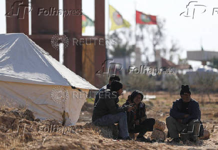 Displaced people who fled Aleppo countryside, sit together near a tent in Tabqa