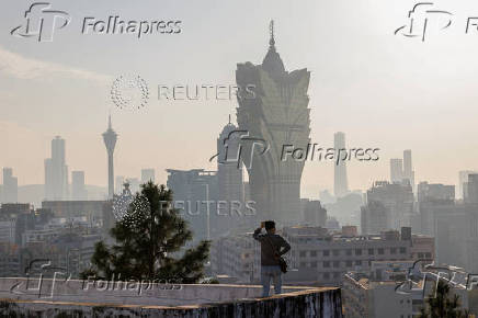 A visitor stands in front of Grand Lisboa casino operated by SJM Holdings, in Macau