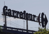 Workers do maintenance on a logo of Carrefour supermarket in Rio de Janeiro