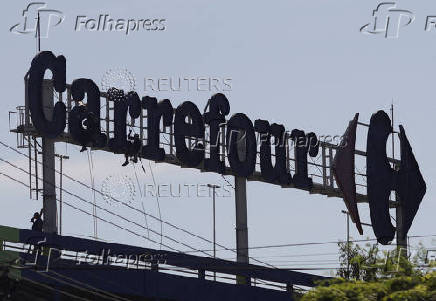 Workers do maintenance on a logo of Carrefour supermarket in Rio de Janeiro