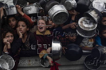 Displaced Palestinians collect donated food in Khan Yunis, southern Gaza