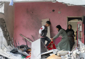 Palestinians inspect damage at the site of an Israeli strike on a house, at Nuseirat refugee camp