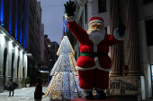 A homeless man walks near a Santa Claus decoration during Christmas Eve in downtown Sao Paulo