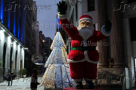 A homeless man walks near a Santa Claus decoration during Christmas Eve in downtown Sao Paulo