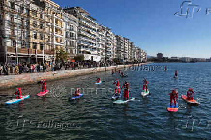 Members of the ThesSUP team wearing Santa Claus costumes paddle off the seafront of Thessaloniki