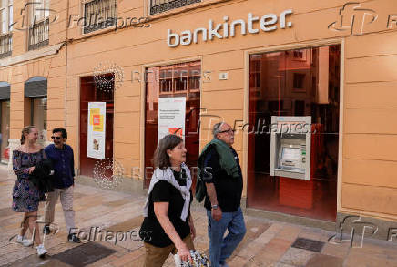 People walk past a Bankinter bank branch office in Malaga