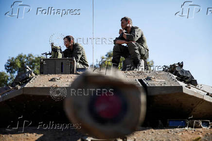 Israeli soldiers sit on a military vehicle near Israel's border with Lebanon