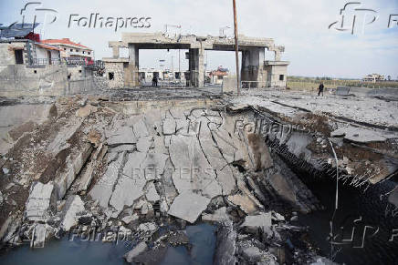 People stand near a damaged site at the Lebanese-Syrian border crossing of Arida