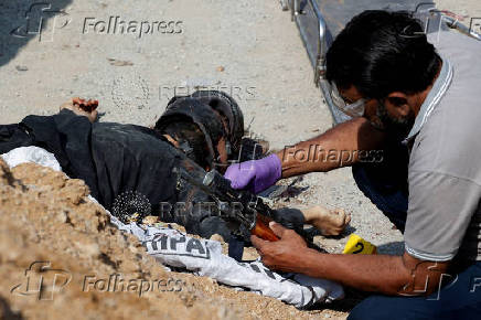 Member of the Crime Scene Unit examines the weapon at the site after a suicide blast in Karachi