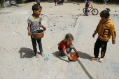 Children hold pots with food, amid the ongoing conflict between Israel and the Palestinian Islamist group Hamas, in Jabalia