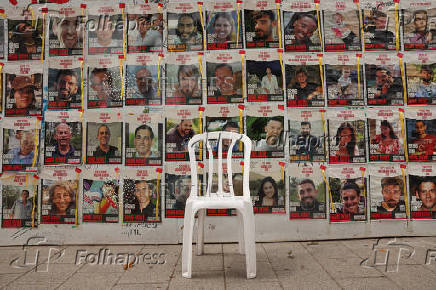 Chair is left in front of posters with pictures of hostages who were kidnapped during the deadly October 7 attack on Israel by Hamas, in Tel Aviv