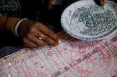 Nasreen sticks artificial gems on an embroidered cloth during her part time job at her residence in Loni town in the northern state of Uttar Pradesh